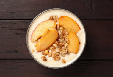 Lezzetli şeftalili yoğurt, tahıl gevreği ve ahşap masada meyveler.