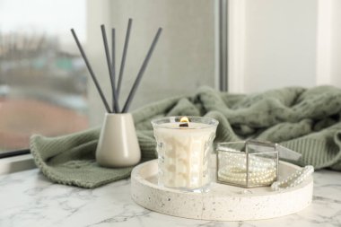 Yanan soya mumu tepsisi ve beyaz pencere pervazında güzel bijouterie.
