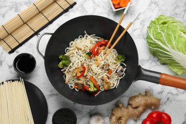 Tavuklu ve sebzeli kızarmış erişteyi beyaz mermer masada karıştır, düz uzan.