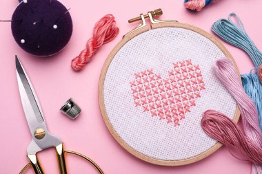 Nakış işlemeli düz kompozisyon ve pembe arka planda farklı dikiş aksesuarları