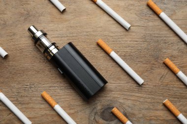 Sigara ve buhar cihazı tahta arka planda, düz yerde. Sigara alternatifi