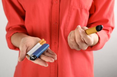Sigaralı bir kadın, arka planda çakmak ve buhar cihazı, yakın plan. Sigara alternatifi