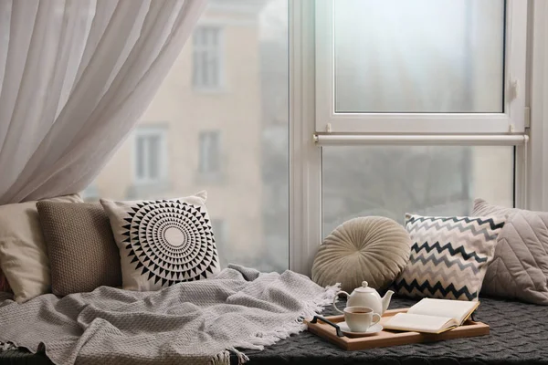 快適なラウンジエリアでは 客室の窓の近くに毛布と柔らかい枕があります — ストック写真