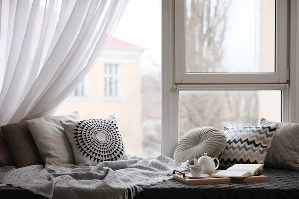 快適なラウンジエリアでは 客室の窓の近くに毛布と柔らかい枕があります — ストック写真