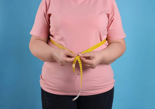 オーバーウェイト女性測定腰でテープでライトブルーの背景 クローズアップ — ストック写真