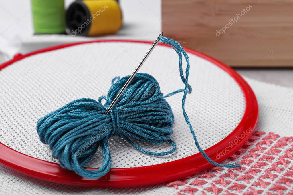 Embroidery hoop with fabric and needle on table, closeup