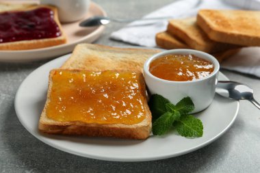 Açık gri masada reçel ve nane ile servis edilen lezzetli tostlar, yakın plan.