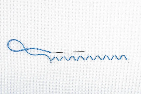 キャンバス上の青い糸と針で作られた刺繍ステッチ トップビュー — ストック写真