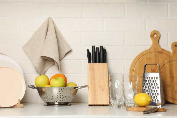 Different cooking utensils, dishware and fruits on kitchen counter