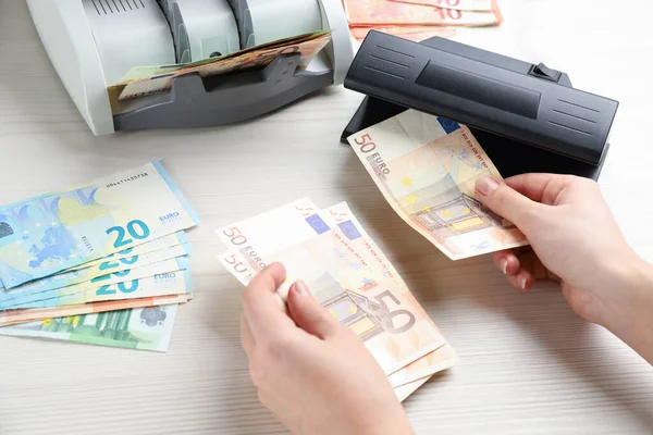 Kvinna Kontrollera Eurosedlar Med Valuta Detektor Vid Vitt Träbord Närbild — Stockfoto