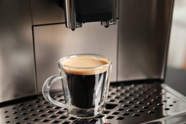 Damla tepsisinde bir fincan taze kahve ile Espresso makinesi, yakın plan.