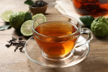 Bir bardak lezzetli bergamot çayı ve ahşap masada taze meyveler, yakın plan.