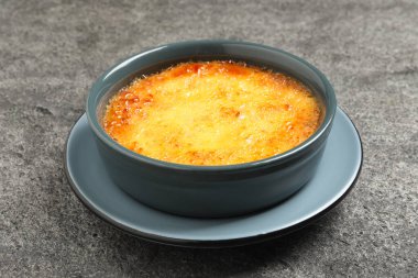 Gri masada seramik çerçeveli leziz creme brulee, yakın plan.