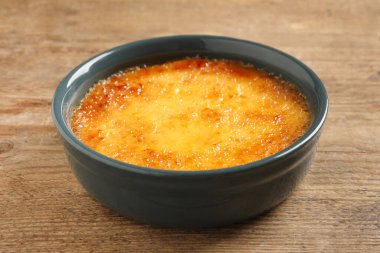 Ahşap masada seramik çerçeveli nefis krema brulee, yakın plan.
