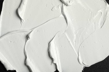 Siyah tuval üzerinde beyaz yağlı boya darbeleri, yakın plan.