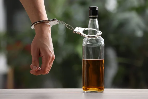 Süchtiger Mann Handschellen Mit Flasche Alkohol Tisch Vor Verschwommenem Hintergrund — Stockfoto
