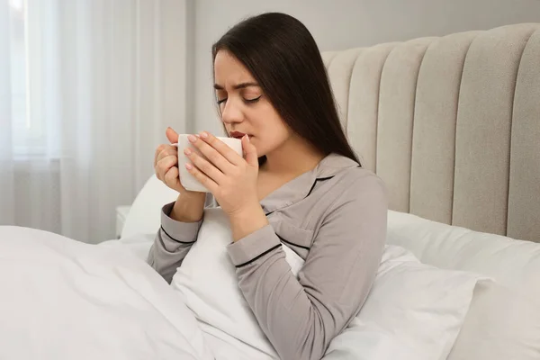 Nemocná Mladá Žena Šálkem Horkého Nápoje Posteli Doma — Stock fotografie