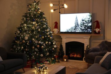 Oturma odasının içinde şöminenin yanında güzel bir Noel ağacı var.