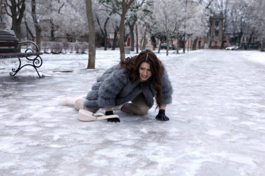 Genç bir kadın parkta kaygan buzlu kaldırıma düştü.