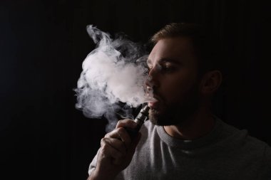 Siyah arka planda elektronik sigara kullanan adam