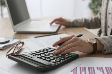 Hesap makinesi olan bir vergi muhasebecisi ofiste çalışıyor, yakın plan.