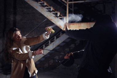 Hırsız gece dışarıda çantasını çalmaya çalışırken biber gazı kullanan bir kadın. Nefsi müdafaa