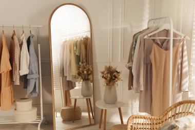 Modern giyinme odasının içinde şık kıyafetler ve güzel kuru çiçekler var.