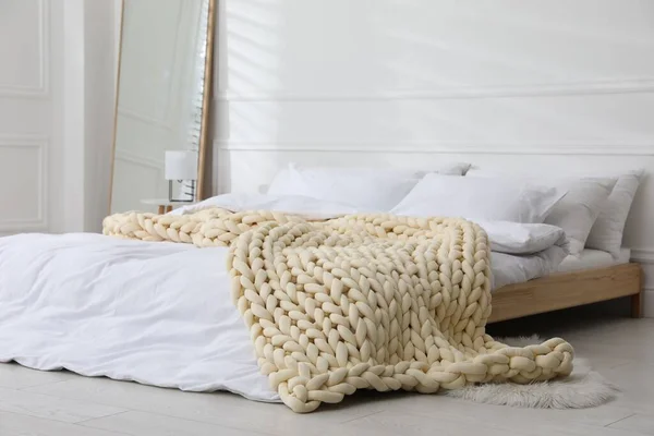 スタイリッシュな部屋のインテリアでベッドの上の柔らかいチュンキーニットブランケット — ストック写真