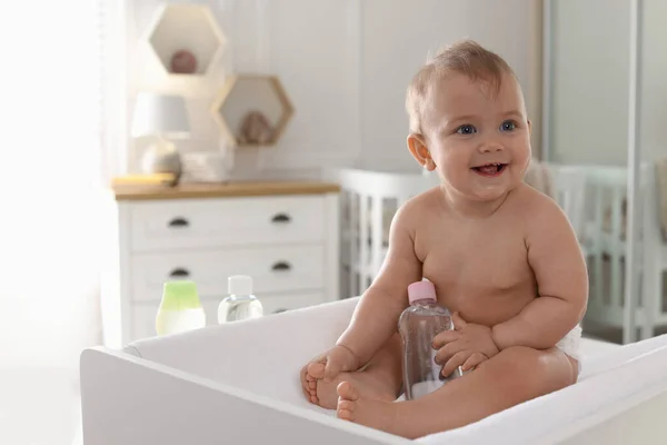 Симпатична Маленька Дитина Пляшкою Масажної Олії Переодягненому Столі Вдома — стокове фото
