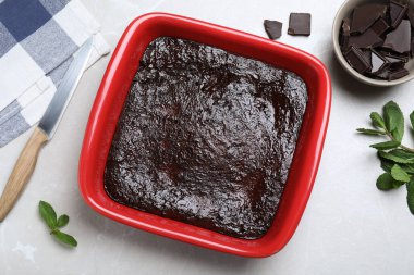 Pişirme kabında nefis browni, çikolata parçaları ve açık gri masada taze nane şekeri.