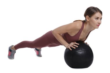 Spor yapan atletik bir kadın, beyaza izole edilmiş ilaç topuyla egzersiz yapıyor.