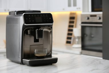 Modern elektrikli espresso makinesi. Mutfaktaki beyaz mermer tezgahta camdan bir fincan kahve.