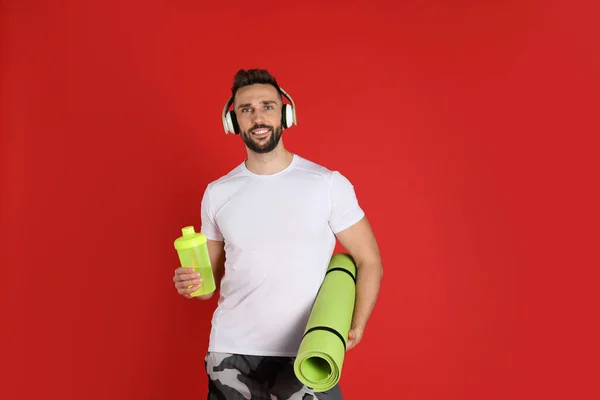 Hombre Guapo Con Auriculares Esterilla Yoga Agitador Sobre Fondo Rojo — Foto de Stock