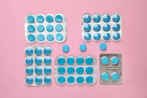 Blue cough drops on pink background, flat lay