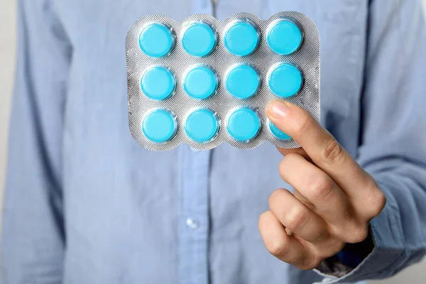 Woman holding blister with cough drops, closeup