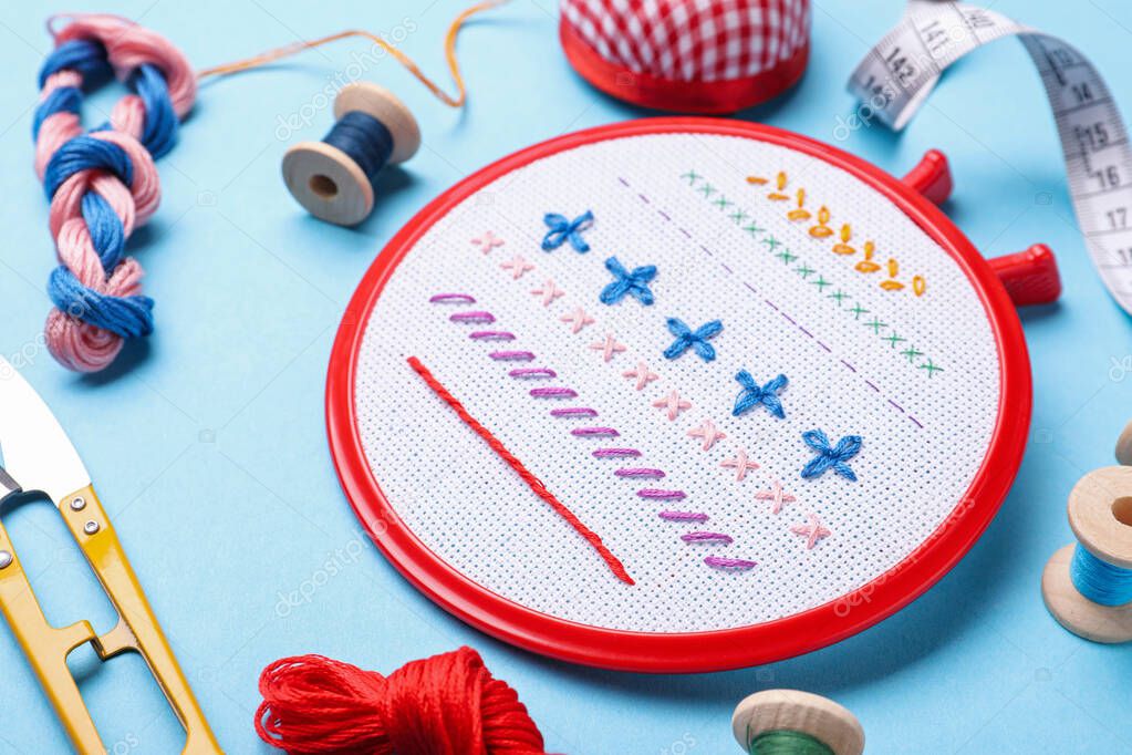 Embroidery and different sewing accessories on light blue background