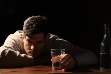 Siyah arka planda alkollü içki bağımlısı adam, cama odaklan.