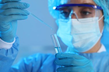 Bilim adamı numuneyi bulanık arkaplanda test tüpüne damlatıyor. Yakın plan. Tıbbi araştırma