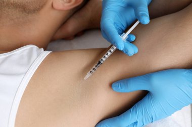 Kozmetik uzmanı, insanın koltuk altına iğne yapıyor, yakın plan. Hiperhidroz tedavisi