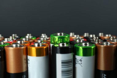 Many AA batteries on grey background, closeup. Space for text clipart