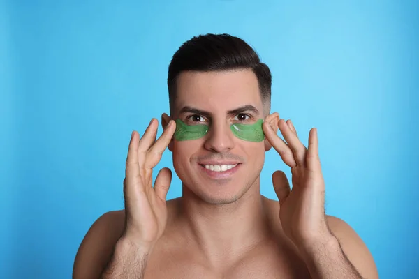 Man Applying Green Eye Patches Light Blue Background — Stock Photo, Image