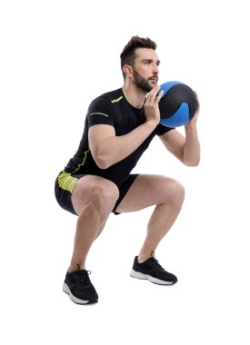 Atletik adam beyaza izole edilmiş ilaç topuyla çömelme yapıyor.