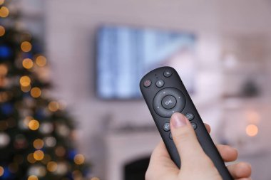 Uzaktan kumandalı bir kadın evde televizyon seyrediyor, kapatıyor. Metin için boşluk