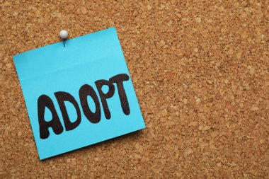 ADOPT kelimesi mantar panoya iğnelenmiş. Metin için boşluk