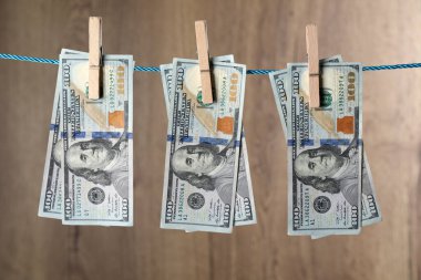 Tahta arka planda ipte asılı duran dolar banknotları