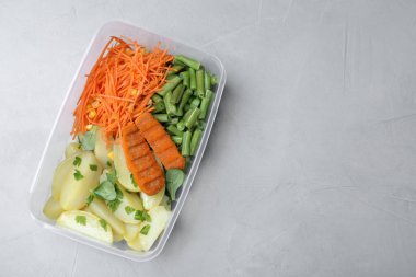 Pirzolalı patatesler ve plastik kapta sebzeler. Masanın üstünde. Metin için boşluk