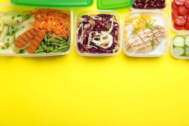 Sarı zemin üzerinde taze yiyecek bulunan plastik kaplar, düz bir zemin. Metin için boşluk