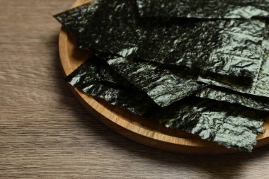 Ahşap masa üzerinde kuru nori çarşaflı tabaklar, yakın plan.