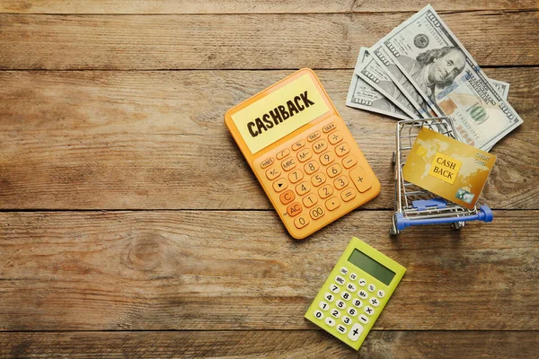 木製の背景にショッピングカート内の計算機 ドル紙幣やクレジットカードは テキストのためのスペースとフラットレイアウト キャッシュバックの概念 — ストック写真