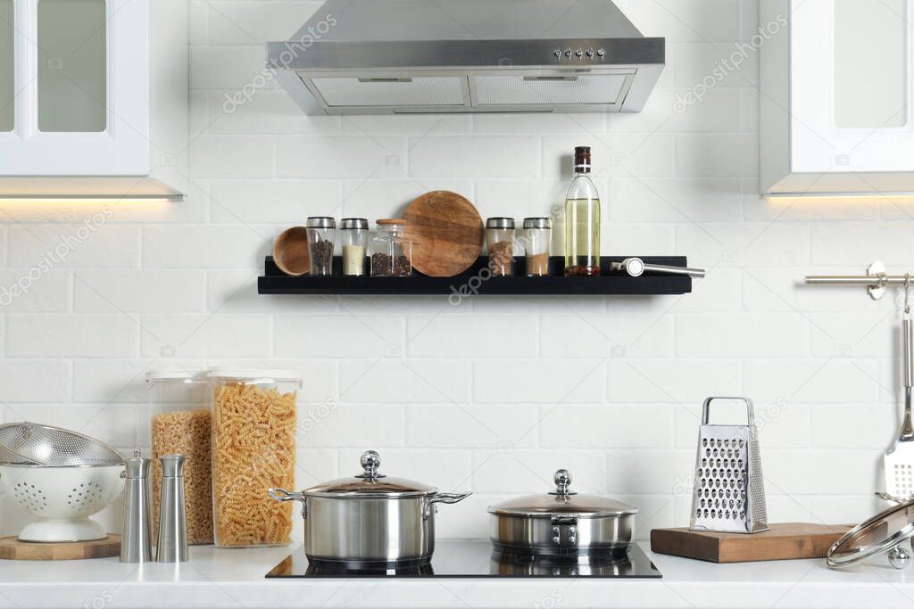 Countertop with different cooking utensils and stove in kitchen